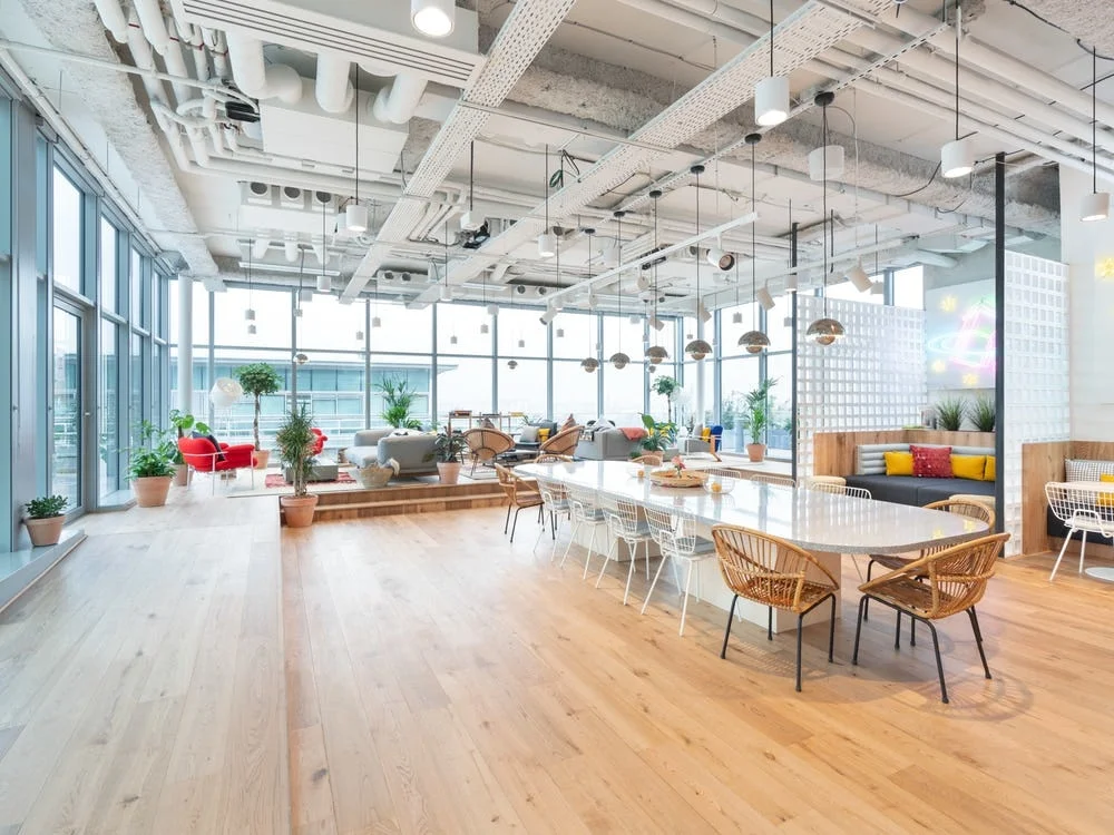 L'espace commun de nos bureaux : grande table, coin salon et baies vitrées