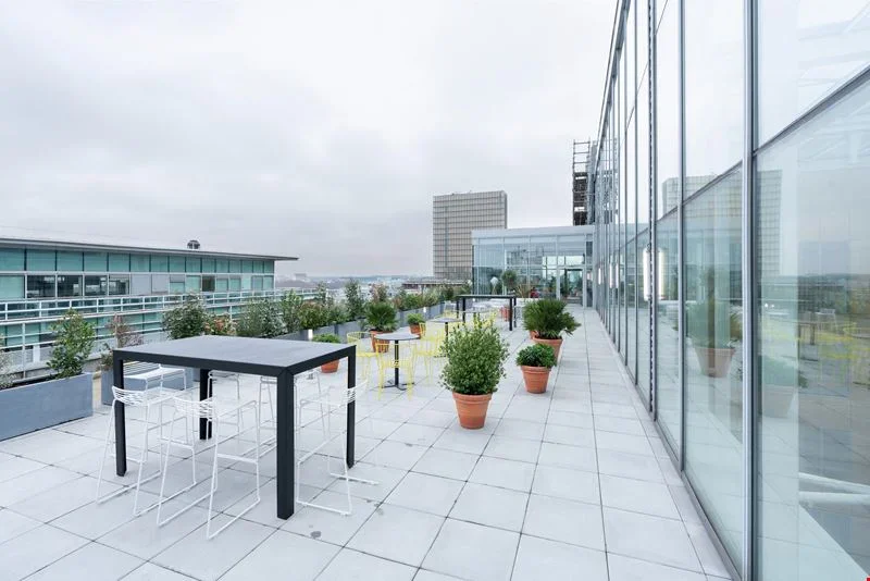 La terrasse de l'immeuble, avec tables hautes et plantes